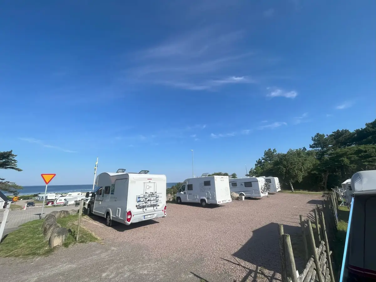 Husbilar på ställplatsen med havet i bakgrunden